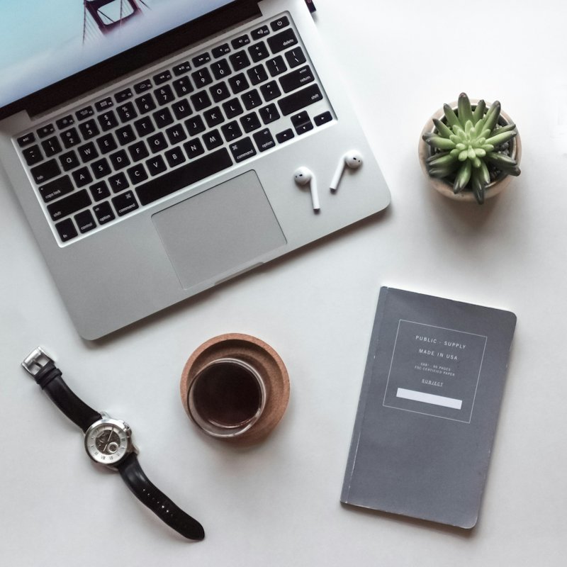 Bright desk with a laptop, coffee, plant and notebook